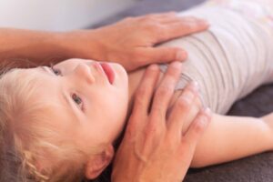 Osteopaat behandelt zacht het middenrif van een kind om spanning te verminderen bij buikpijnklachten.